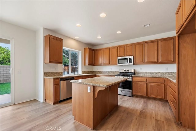 1984 Bronte Rd, San Jacinto, CA 92583 - kitchen with light stone counters, brown cabinetry, a kitchen island, and appliances with stainless steel finishes