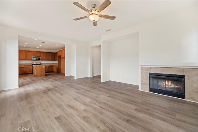 1984 Bronte Rd, San Jacinto, CA 92583 - unfurnished living room featuring a tiled fireplace, a ceiling fan, light wood finished floors, and visible vents