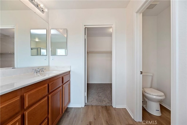 1984 Bronte Rd, San Jacinto, CA 92583 - bathroom with vanity, a walk in closet, toilet, baseboards, and wood finished floors