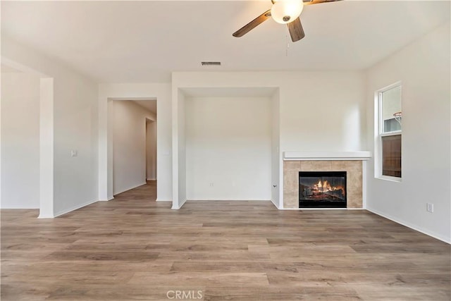 1984 Bronte Rd, San Jacinto, CA 92583 - unfurnished living room with visible vents, wood finished floors, a tiled fireplace, and a ceiling fan