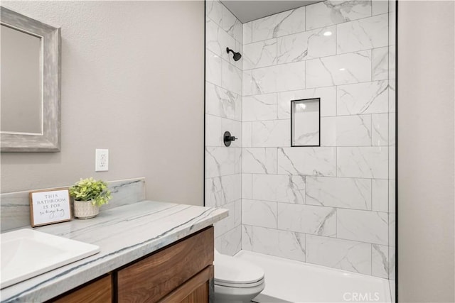 bathroom featuring a tile shower, toilet, and vanity