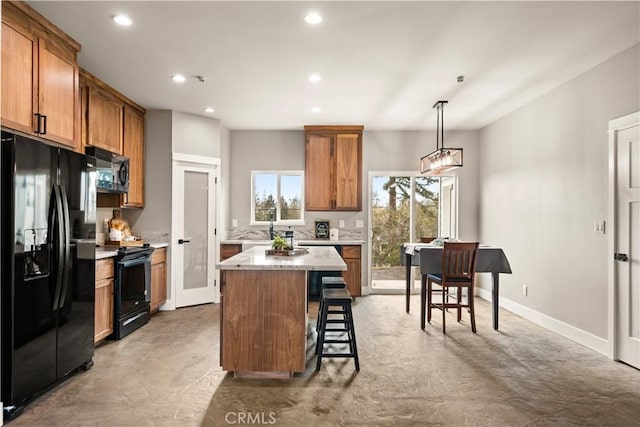 kitchen with brown cabinetry, recessed lighting, black appliances, and a kitchen island