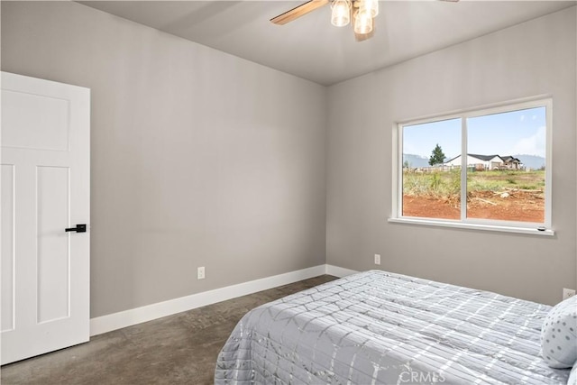 bedroom featuring baseboards, a ceiling fan, and concrete flooring