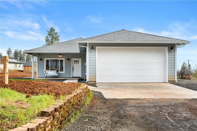 ranch-style house with roof with shingles, driveway, a porch, an attached garage, and ceiling fan