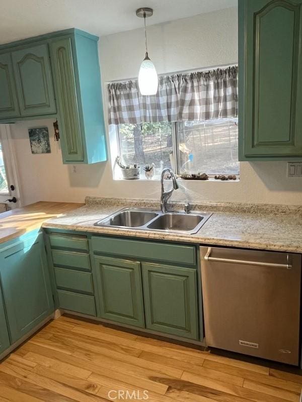 kitchen with light countertops, green cabinetry, stainless steel dishwasher, and a sink