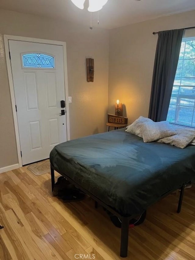 bedroom featuring light wood finished floors and baseboards
