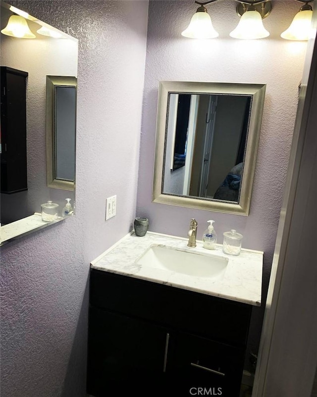 bathroom with a textured wall and vanity