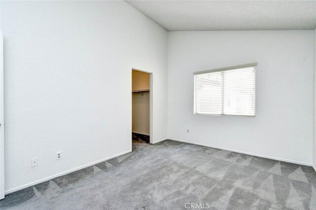unfurnished bedroom with baseboards, a spacious closet, and carpet floors