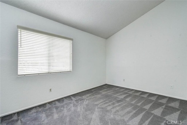 carpeted spare room with a textured ceiling and lofted ceiling
