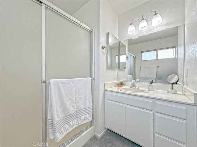 full bathroom featuring a textured wall, vanity, and a stall shower