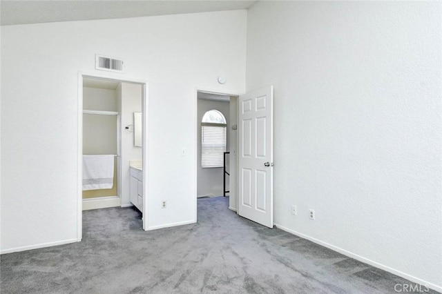unfurnished bedroom with baseboards, connected bathroom, visible vents, high vaulted ceiling, and carpet