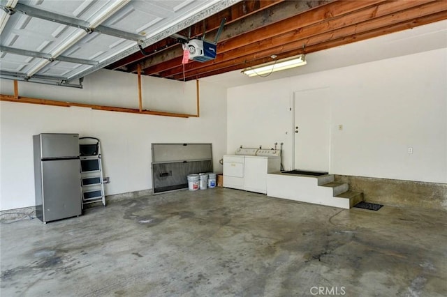 garage with washer and dryer, a garage door opener, and freestanding refrigerator