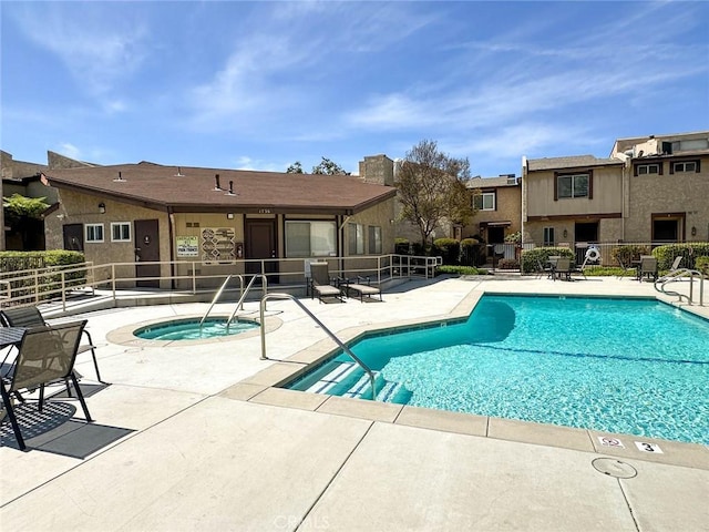 pool with a patio area, a residential view, fence, and a hot tub