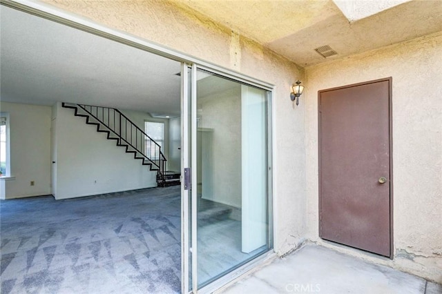 view of exterior entry featuring stucco siding and visible vents