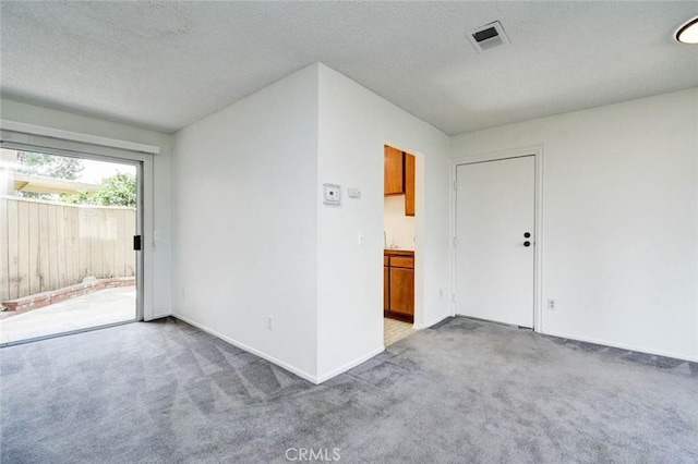 unfurnished room featuring a textured ceiling, visible vents, and carpet
