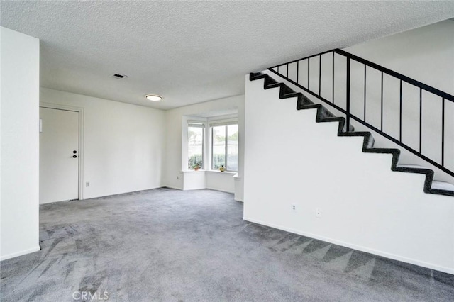interior space with carpet floors, visible vents, a textured ceiling, and stairs