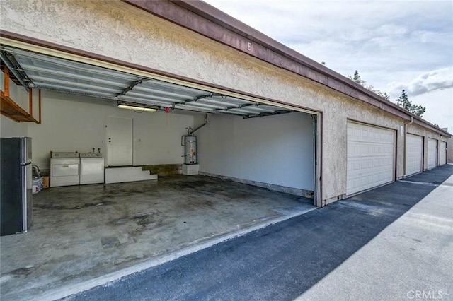 garage with freestanding refrigerator, washing machine and dryer, and strapped water heater