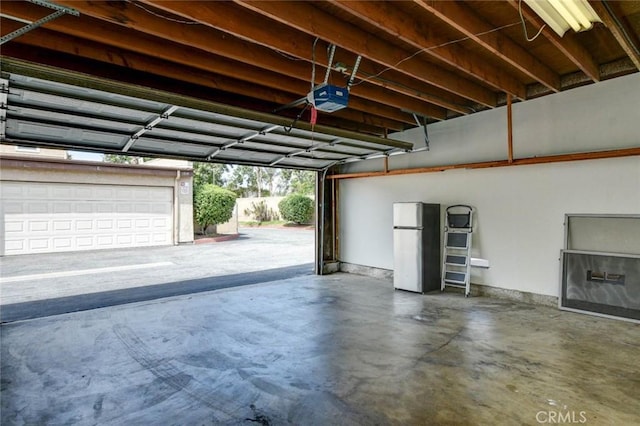 garage with freestanding refrigerator and a garage door opener