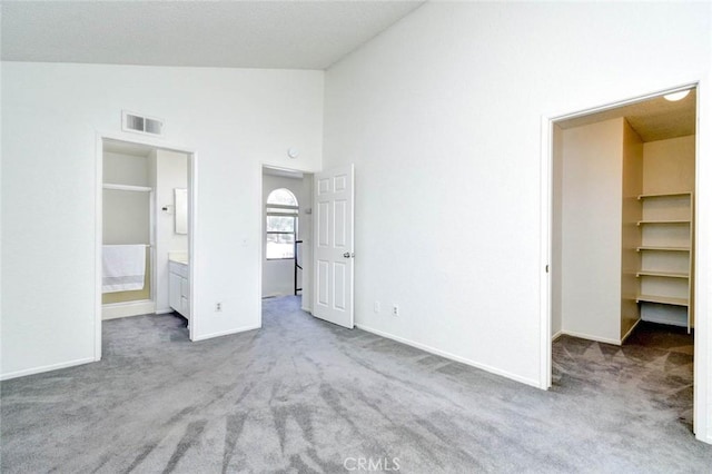 unfurnished bedroom featuring a walk in closet, carpet flooring, visible vents, and baseboards