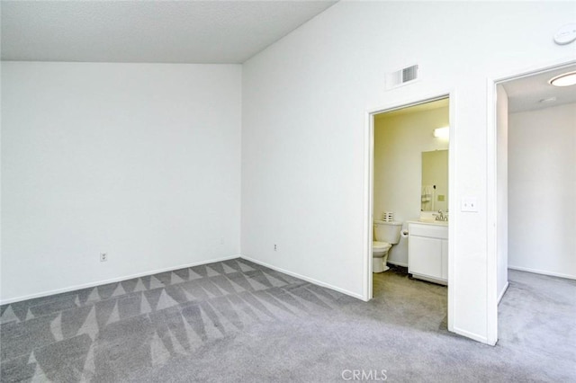 unfurnished bedroom featuring baseboards, connected bathroom, visible vents, carpet, and a sink