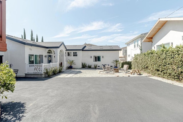 view of front of home with a residential view, a patio, stucco siding, and a fire pit