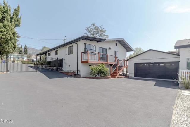 view of front of home featuring fence, aphalt driveway, stucco siding, stairway, and a gate