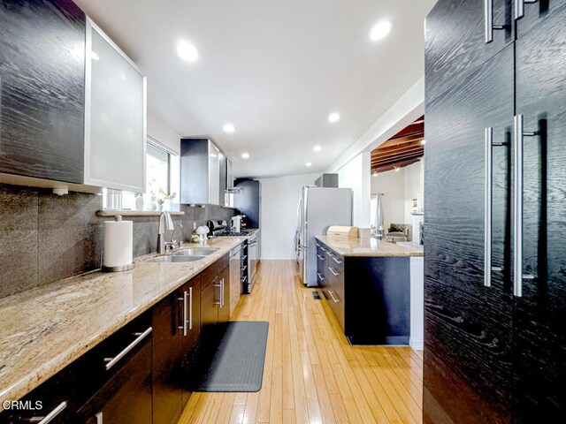 kitchen with stainless steel appliances, light stone countertops, decorative backsplash, and a sink
