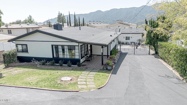 view of front facade with fence, a front lawn, a gate, a mountain view, and a chimney