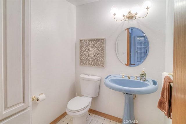 bathroom featuring toilet, baseboards, and a sink