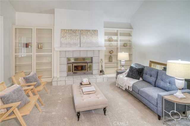 living room featuring a tile fireplace, carpet, and built in shelves