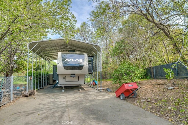 view of vehicle parking featuring fence, a carport, and concrete driveway