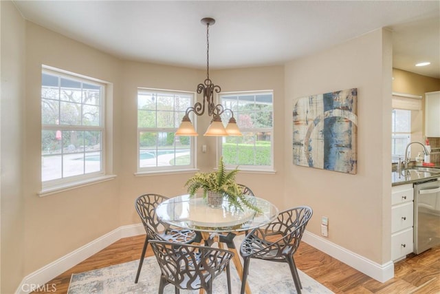 dining area featuring baseboards, light wood-style flooring, and a notable chandelier