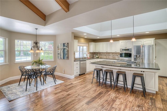 kitchen with a sink, stainless steel appliances, light wood-style flooring, a center island, and white cabinets