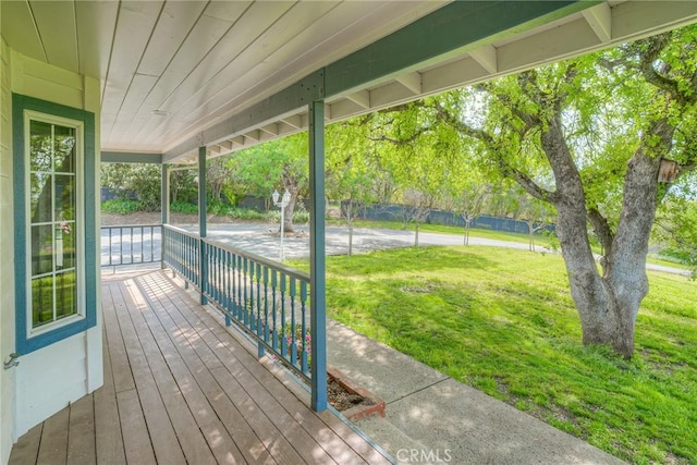 wooden terrace featuring covered porch and a lawn