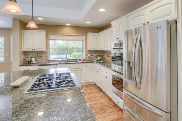 kitchen with white cabinetry, hanging light fixtures, appliances with stainless steel finishes, and a sink
