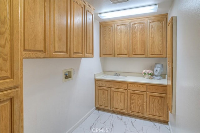 laundry area with baseboards, marble finish floor, hookup for a washing machine, a sink, and cabinet space
