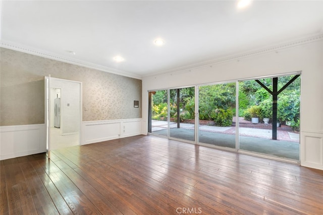empty room featuring a wealth of natural light, wood-type flooring, wainscoting, and crown molding
