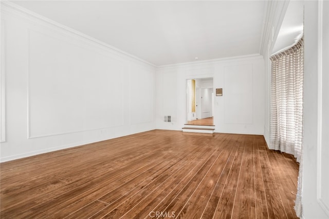 unfurnished room featuring a decorative wall, ornamental molding, and hardwood / wood-style flooring
