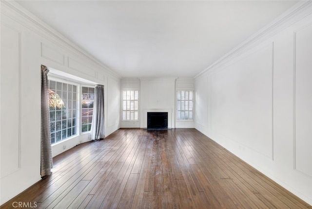 unfurnished living room featuring a decorative wall, ornamental molding, a fireplace with flush hearth, and dark wood-type flooring