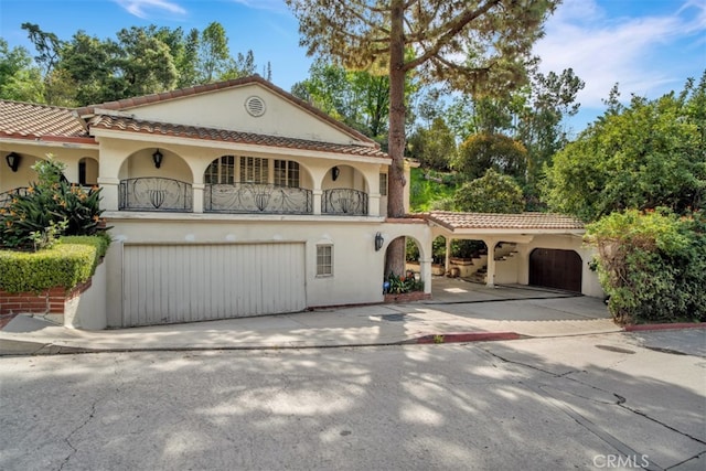 view of front of home with concrete driveway, a balcony, a tiled roof, and stucco siding
