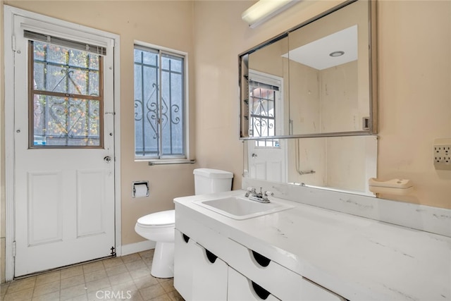 bathroom with toilet, vanity, and baseboards