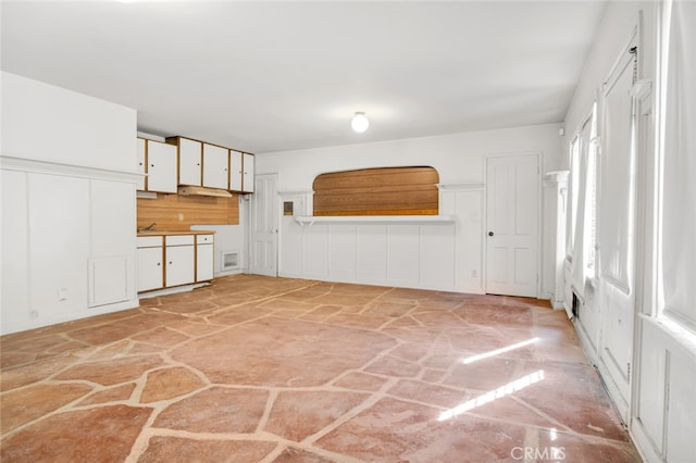 kitchen with visible vents, a sink, white cabinetry, and stone flooring