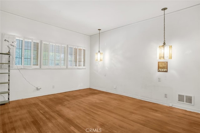 unfurnished room with wood finished floors, baseboards, and visible vents
