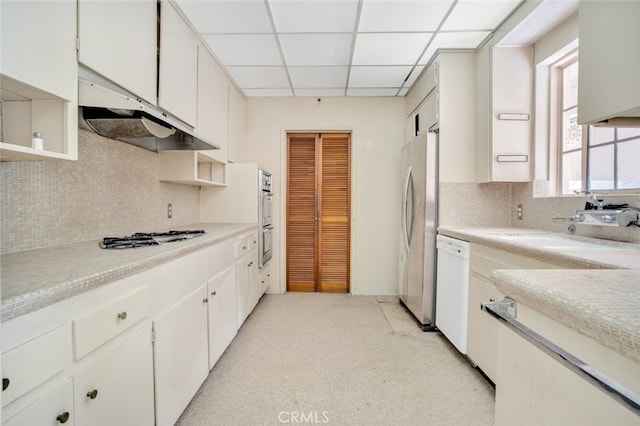 kitchen with a paneled ceiling, light countertops, backsplash, white cabinetry, and appliances with stainless steel finishes
