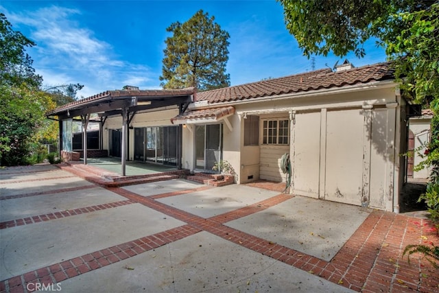 rear view of house with a patio, stucco siding, and a tile roof