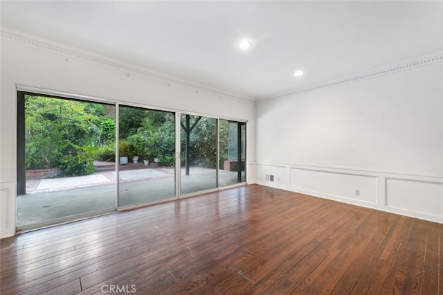 empty room with a decorative wall, wood-type flooring, wainscoting, and visible vents