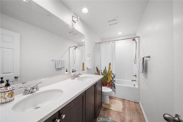 bathroom with double vanity, a sink, toilet, and wood finished floors