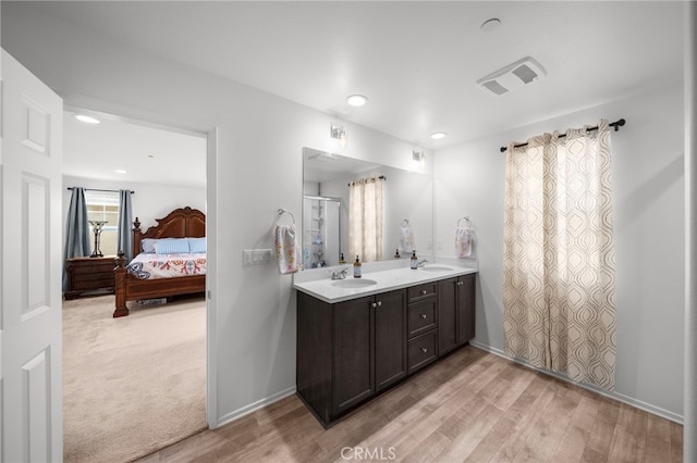 ensuite bathroom with ensuite bathroom, visible vents, wood finished floors, and a sink