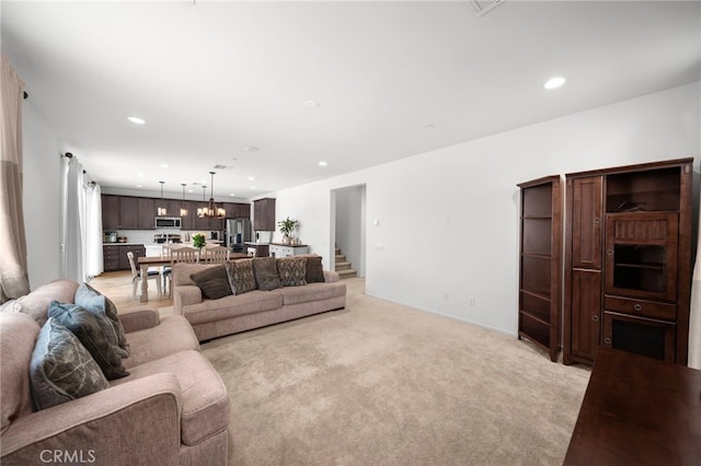 living room featuring stairs, recessed lighting, a notable chandelier, and light colored carpet