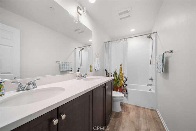 full bathroom featuring double vanity, a sink, toilet, and wood finished floors